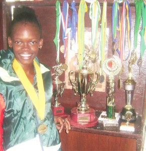 Jevina Straker posing with a few of her trophies and medals at home yesterday. (Rawle Toney photo)  